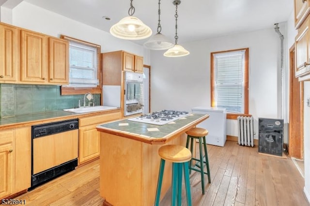 kitchen with radiator, white gas stovetop, sink, dishwasher, and a kitchen island