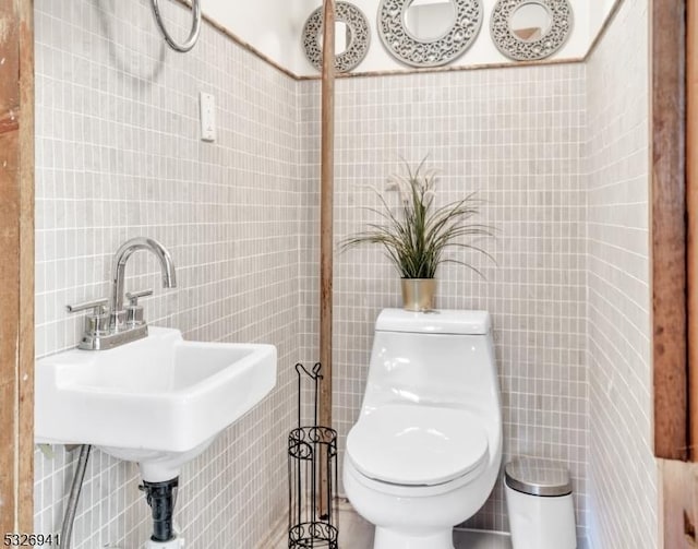 bathroom with toilet, tile walls, and sink