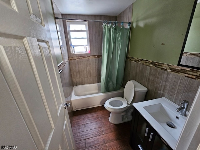 full bathroom with shower / bath combination with curtain, vanity, tile walls, hardwood / wood-style floors, and toilet