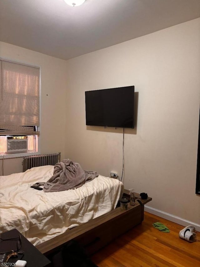 bedroom featuring cooling unit, radiator, and hardwood / wood-style floors