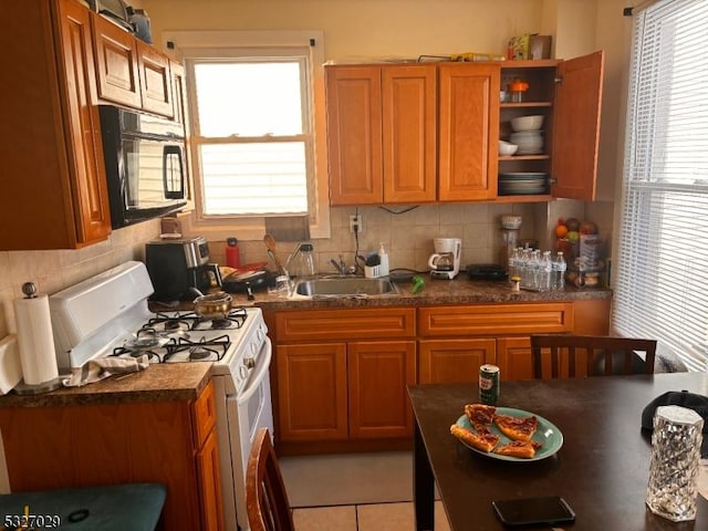 kitchen with sink, a wealth of natural light, decorative backsplash, and gas range gas stove