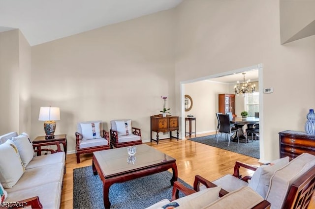 living room with high vaulted ceiling, light wood-type flooring, and a notable chandelier