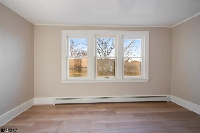 empty room with a wealth of natural light, crown molding, a baseboard radiator, and light hardwood / wood-style floors