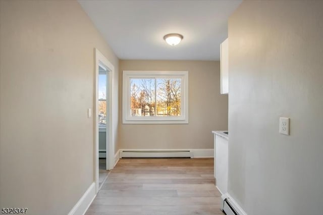 hallway with light hardwood / wood-style flooring and baseboard heating