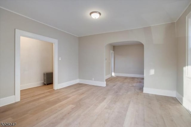 empty room featuring radiator heating unit and light hardwood / wood-style flooring