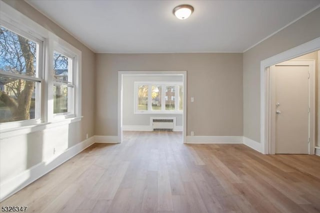 spare room featuring radiator and light hardwood / wood-style flooring