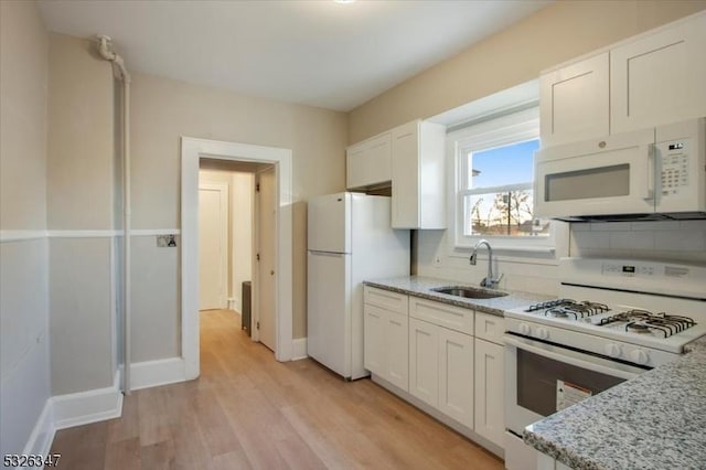 kitchen with sink, white cabinets, white appliances, and light hardwood / wood-style flooring