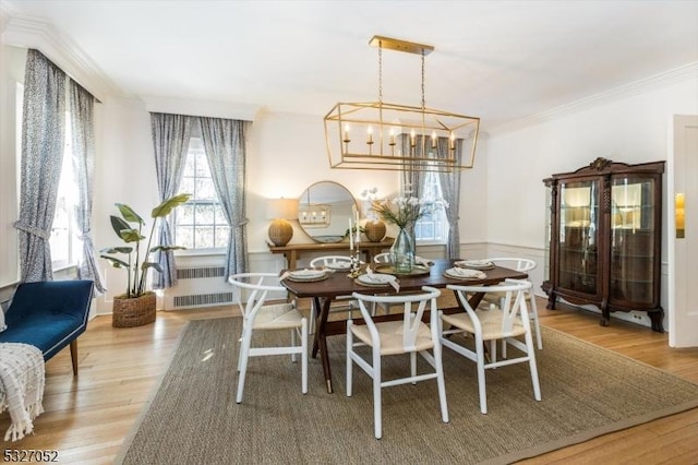 dining space with wood-type flooring, radiator heating unit, a notable chandelier, and ornamental molding