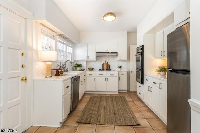 kitchen featuring sink, white cabinetry, light tile patterned floors, decorative backsplash, and stainless steel appliances