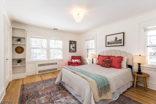 bedroom featuring radiator heating unit, ornamental molding, and light hardwood / wood-style flooring