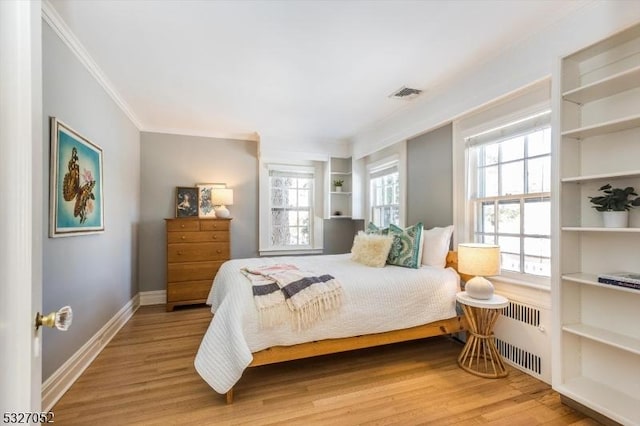 bedroom featuring crown molding, radiator heating unit, multiple windows, and light hardwood / wood-style floors