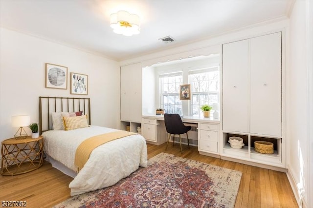 bedroom featuring radiator, crown molding, and light hardwood / wood-style flooring