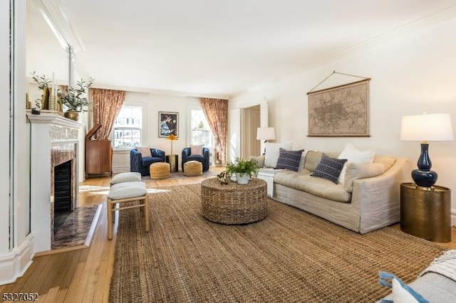 living room featuring hardwood / wood-style flooring, a high end fireplace, and ornamental molding