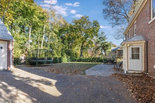 view of yard featuring a trampoline and a patio area