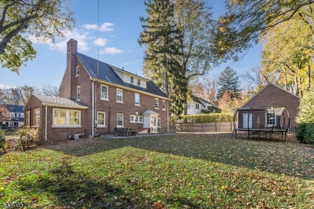 rear view of house featuring a yard and a trampoline