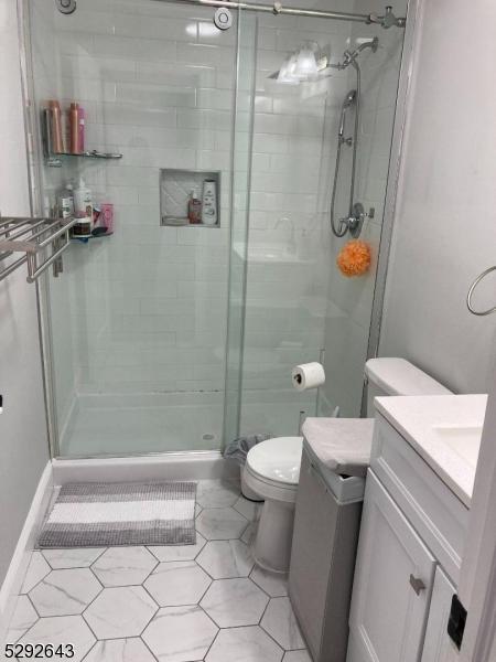 bathroom featuring tile patterned floors, vanity, an enclosed shower, and toilet