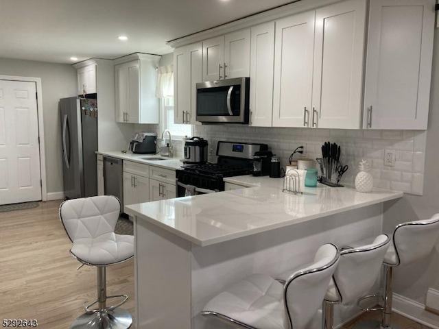 kitchen with a kitchen breakfast bar, kitchen peninsula, white cabinets, and stainless steel appliances