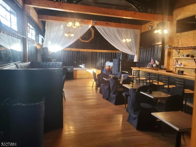 interior space featuring beamed ceiling, wood-type flooring, and a notable chandelier