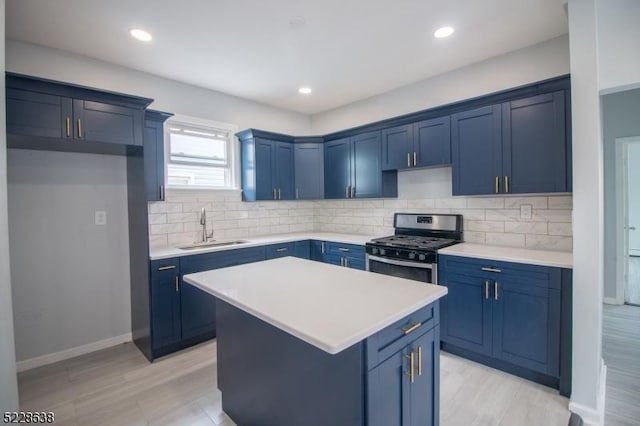 kitchen featuring a center island, stainless steel gas range oven, blue cabinets, sink, and tasteful backsplash