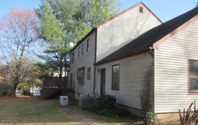 view of property exterior featuring a lawn, central AC, and a deck