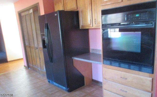 kitchen with light brown cabinets, light hardwood / wood-style flooring, and black appliances