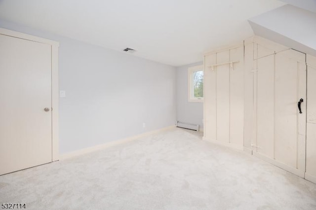 unfurnished bedroom featuring light colored carpet and a baseboard heating unit