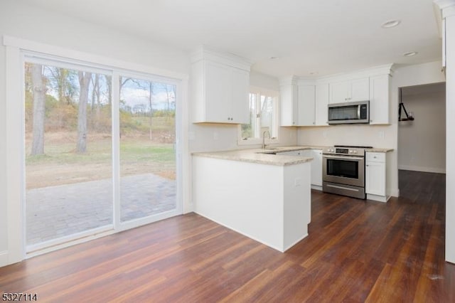 kitchen with white cabinetry, sink, stainless steel appliances, dark hardwood / wood-style flooring, and kitchen peninsula