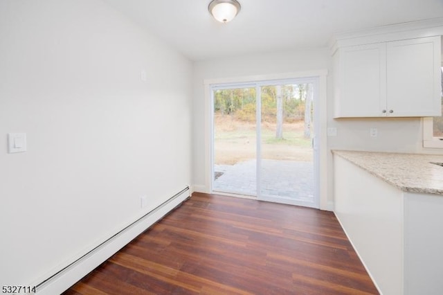 unfurnished dining area featuring dark hardwood / wood-style flooring and a baseboard heating unit