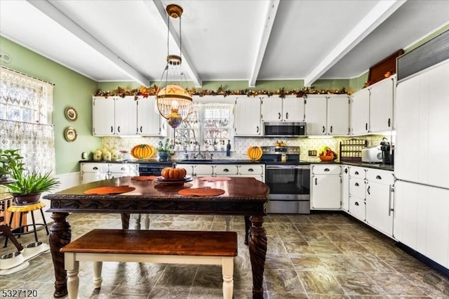 kitchen with appliances with stainless steel finishes, sink, beam ceiling, white cabinetry, and hanging light fixtures