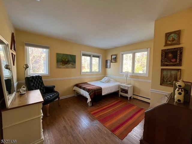 bedroom with dark hardwood / wood-style floors and baseboard heating