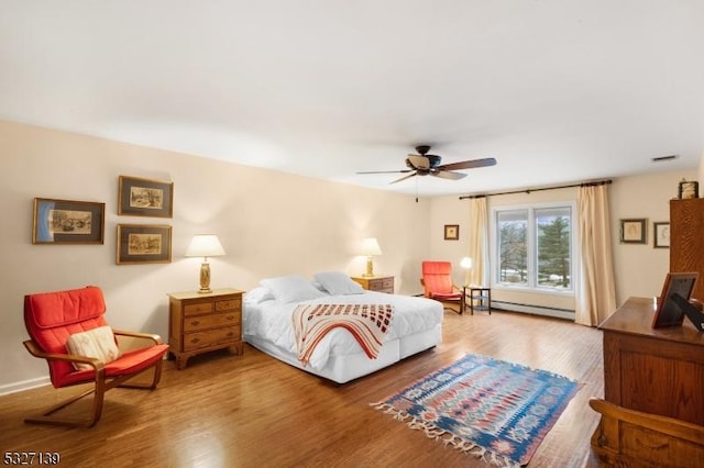 bedroom with ceiling fan, a baseboard radiator, and wood-type flooring