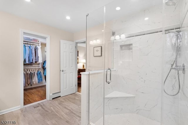 bathroom with hardwood / wood-style flooring, a shower with shower door, and baseboard heating