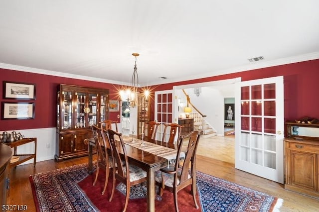 dining space featuring crown molding, wood-type flooring, and a chandelier