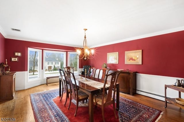 dining space with a notable chandelier, ornamental molding, hardwood / wood-style floors, and baseboard heating