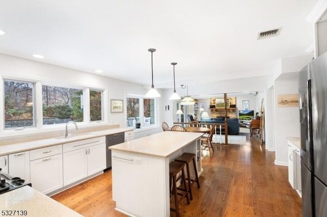 kitchen with sink, white cabinetry, a center island, stainless steel fridge, and a kitchen breakfast bar