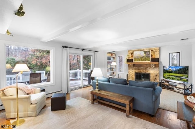 living room featuring beamed ceiling, a baseboard radiator, a fireplace, and light hardwood / wood-style flooring