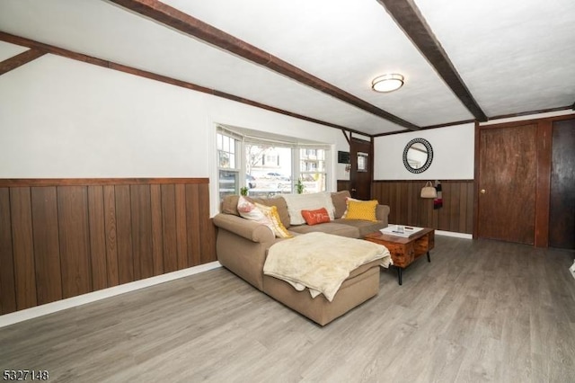 living room with beamed ceiling, light wood-type flooring, and wood walls