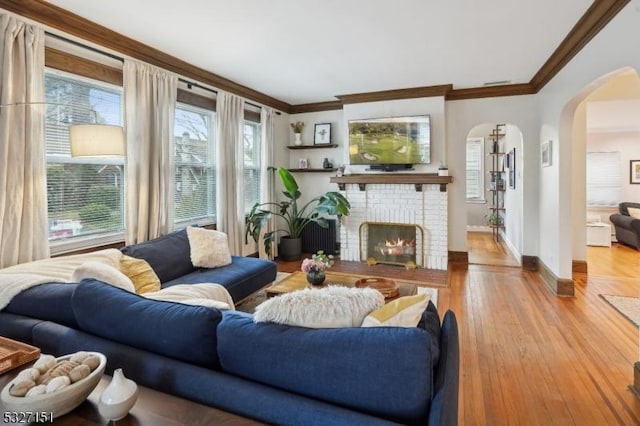 living room with light wood-type flooring, a fireplace, and ornamental molding