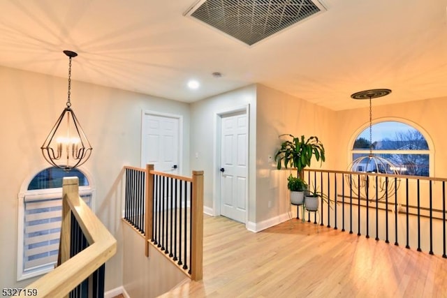 hall featuring an inviting chandelier, hardwood / wood-style flooring, and a baseboard radiator