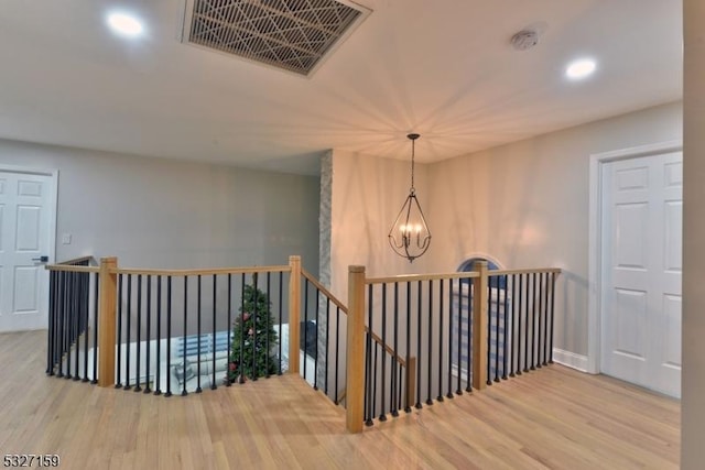 hallway featuring an inviting chandelier and wood-type flooring