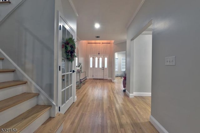 entryway with crown molding and light hardwood / wood-style floors