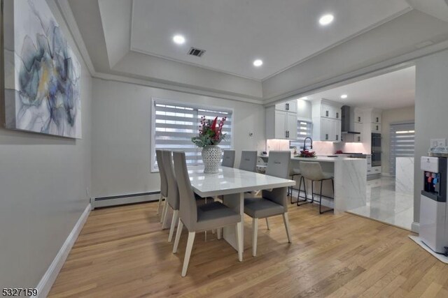 dining area featuring a baseboard radiator, crown molding, and light hardwood / wood-style floors