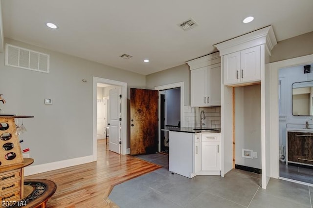 kitchen featuring tasteful backsplash, sink, white cabinets, and light wood-type flooring