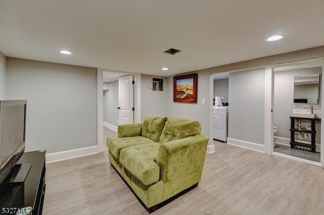 living room featuring washer / dryer and light hardwood / wood-style floors