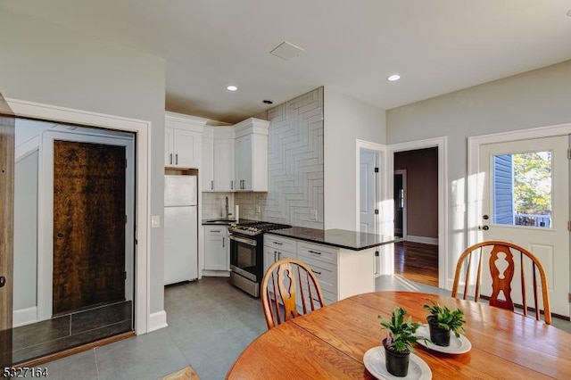 kitchen with white cabinetry, tasteful backsplash, gas stove, and white fridge