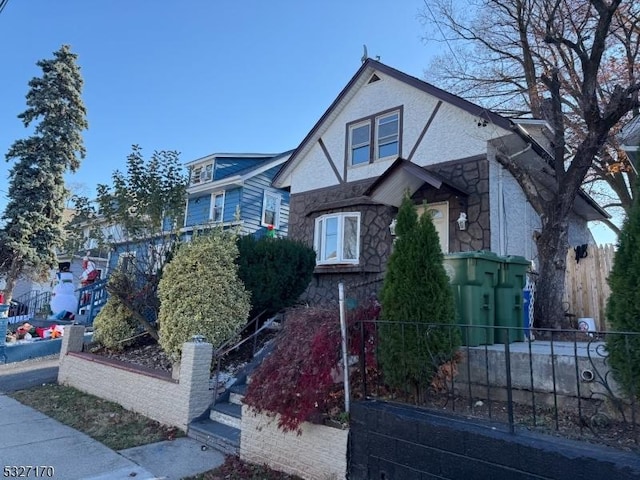 view of front of home featuring stone siding and fence