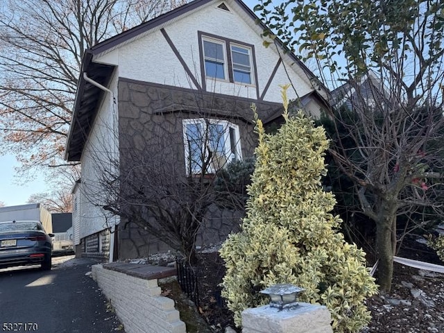 view of side of property featuring stone siding and stucco siding