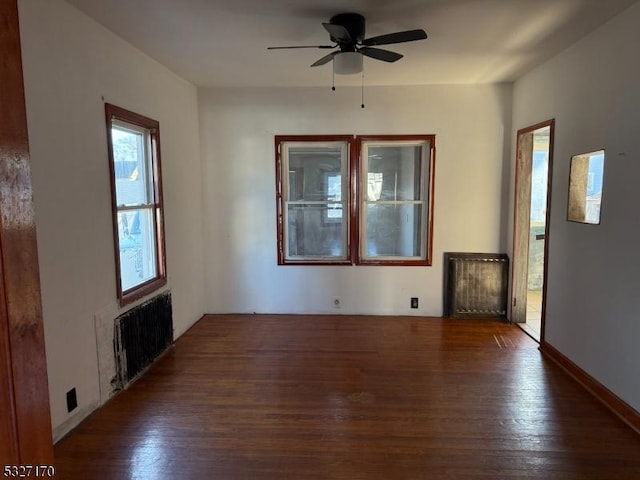 spare room featuring radiator, a ceiling fan, and wood finished floors