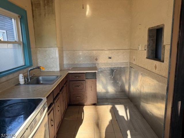 kitchen with light countertops, light tile patterned flooring, a sink, and white range with electric stovetop