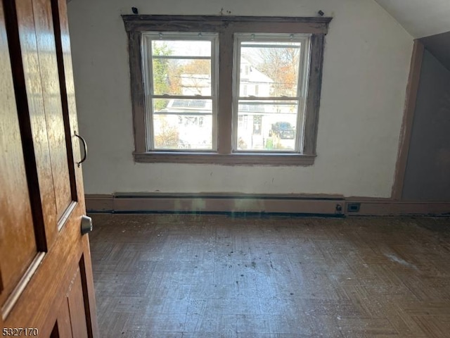 empty room featuring lofted ceiling and baseboard heating